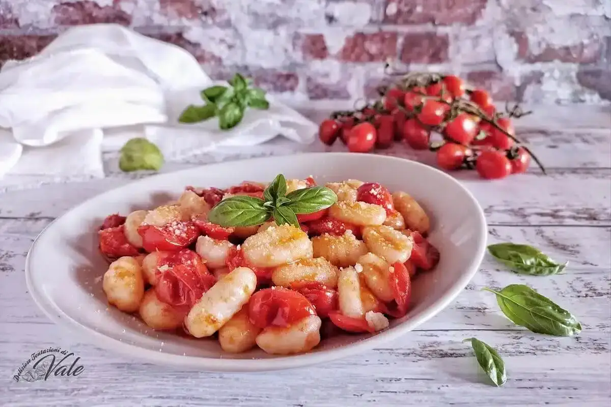 Gnocchi al pomodoro freschi, conditi con pomodorini succosi e basilico profumato, un piatto semplice e gustoso.