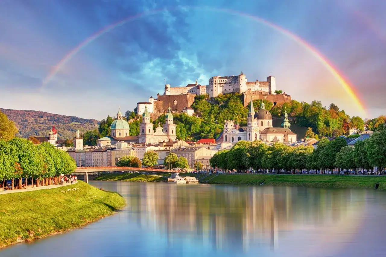 Salzburg co zobaczyć: twierdza Hohensalzburg i katedra na tle tęczy nad rzeką Salzach.