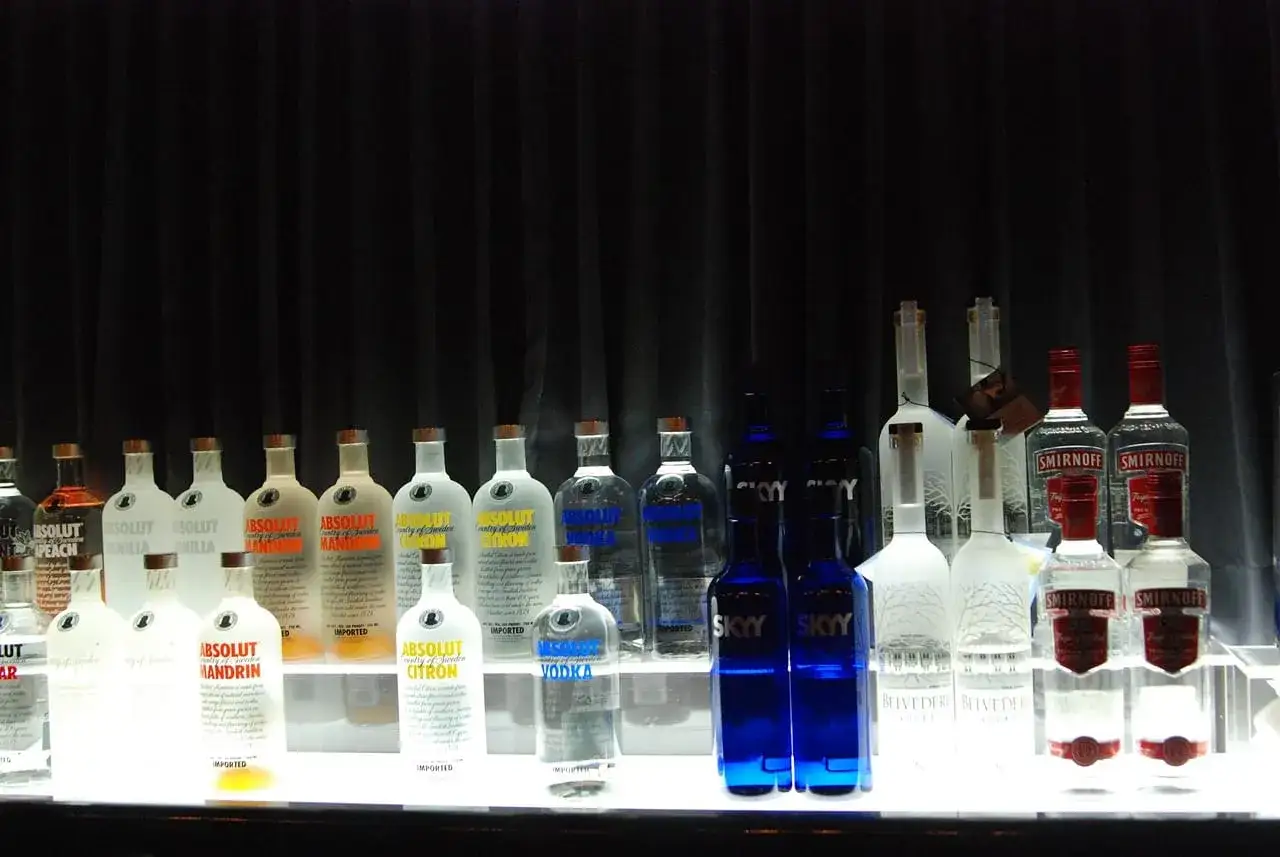 Rząd butelek wódki Absolut i Smirnoff. Czy wódka może się zepsuć? Termin przydatności do spożycia jest długi, ale warto sprawdzić.