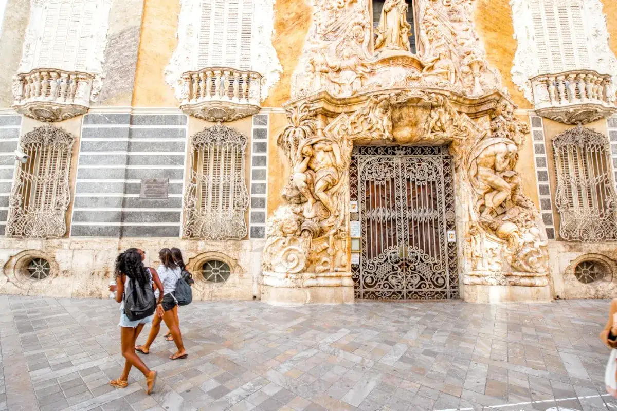 Dos chicas pasean frente a una fachada ornamentada, buscando museos gratis en Valencia.