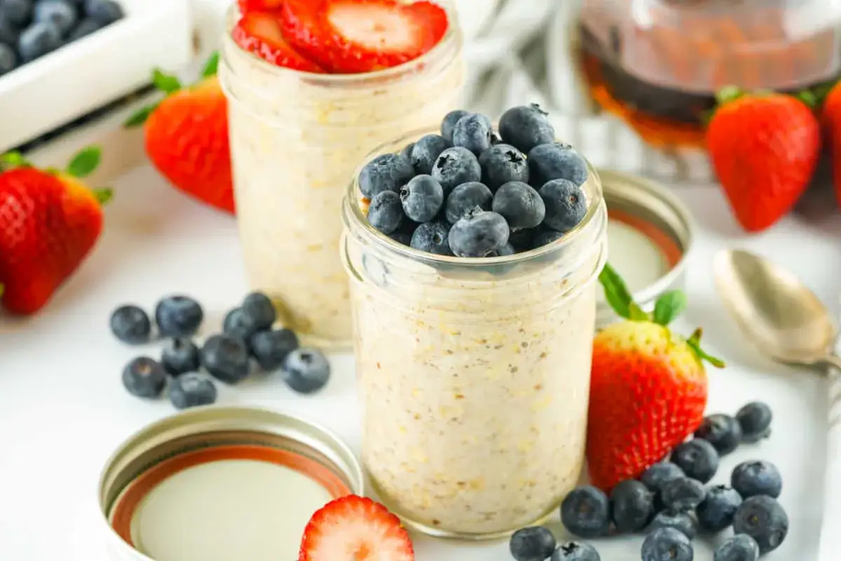 Två burkar med overnight oats recept, toppade med blåbär och jordgubbar. Enkelt och gott!