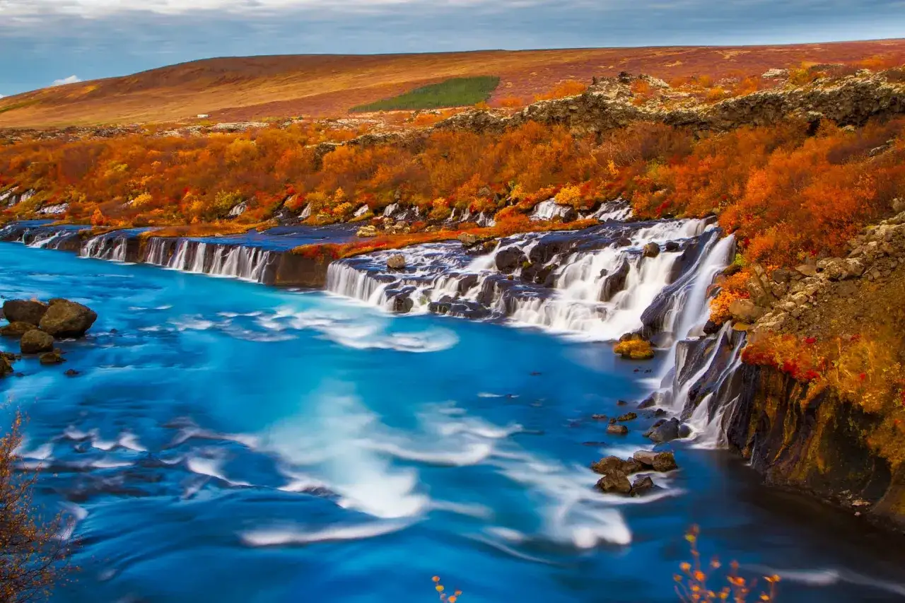 Wodospad na Islandii, jesienne barwy otaczającej roślinności i turkusowa woda. Islandia klimat w pełni swojej jesiennej krasy.