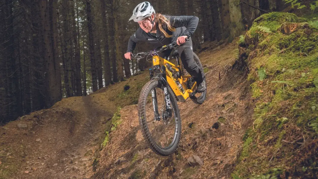 A mountain biker navigates a steep, wooded trail, showcasing the thrill of downhill mtb trails.