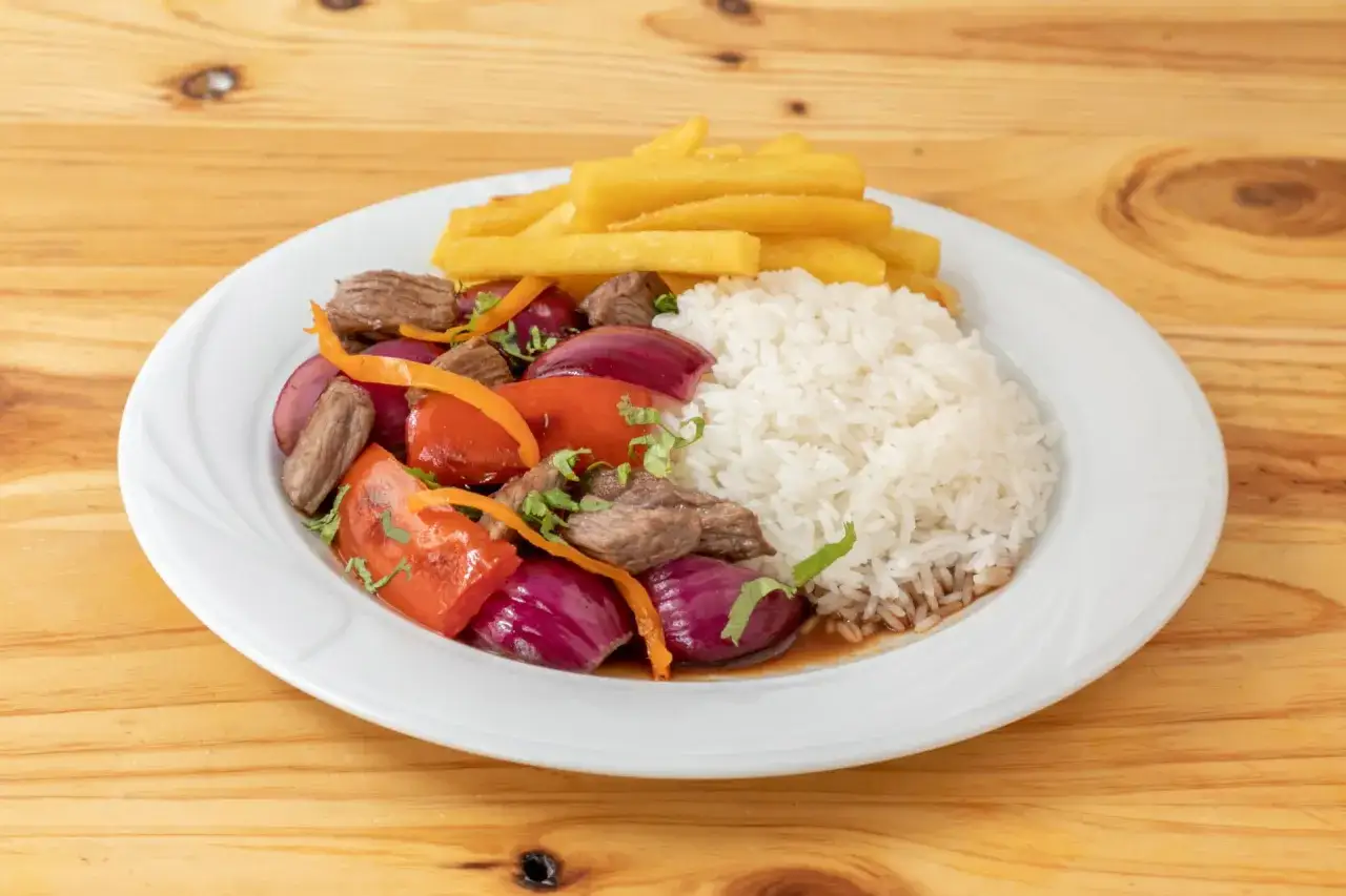 Lomo saltado con arroz blanco, papas fritas, carne, cebolla roja y tomate. Un plato peruano delicioso.