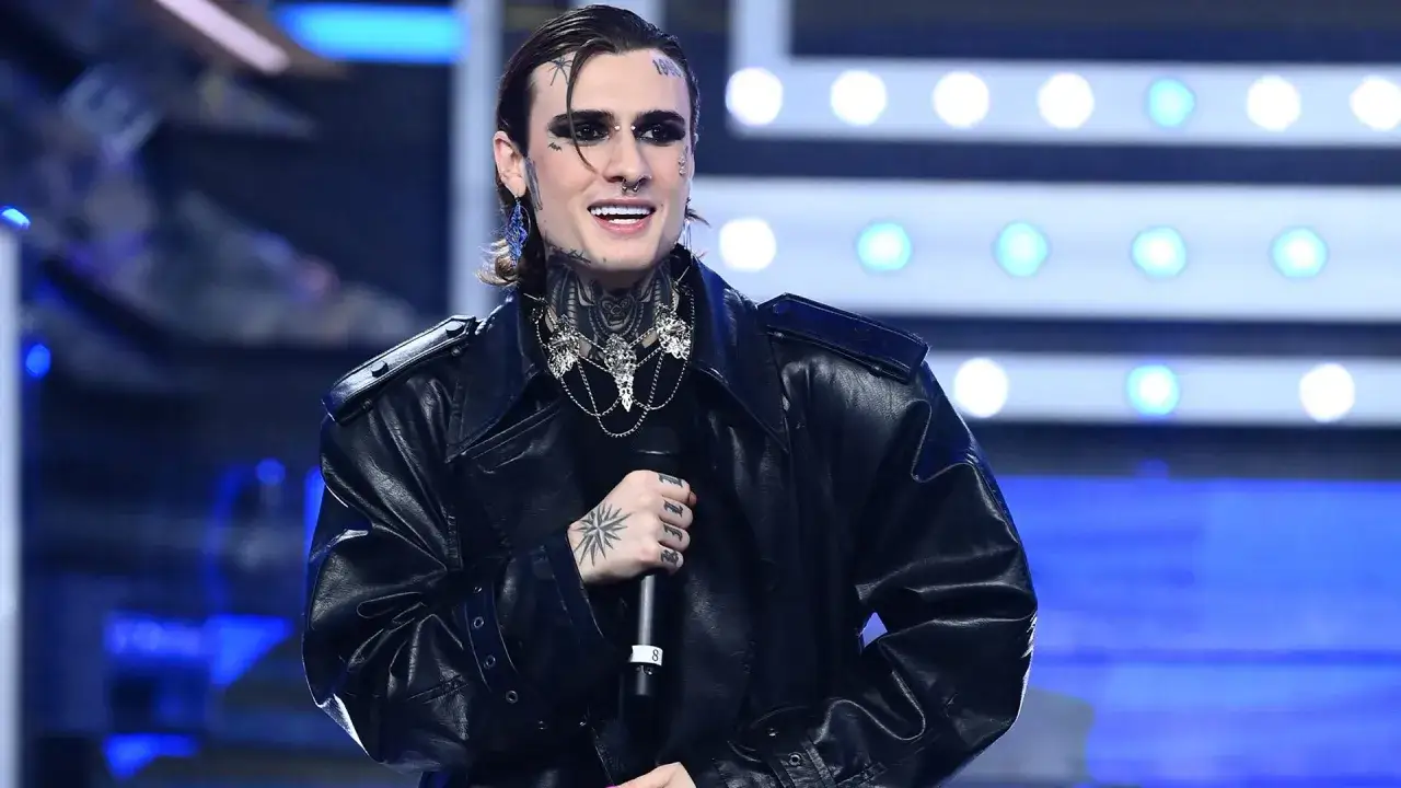 Artista con trucco audace e tatuaggi, indossa una giacca di pelle nera e una collana vistosa, un'icona dallo stile rosa chemical.