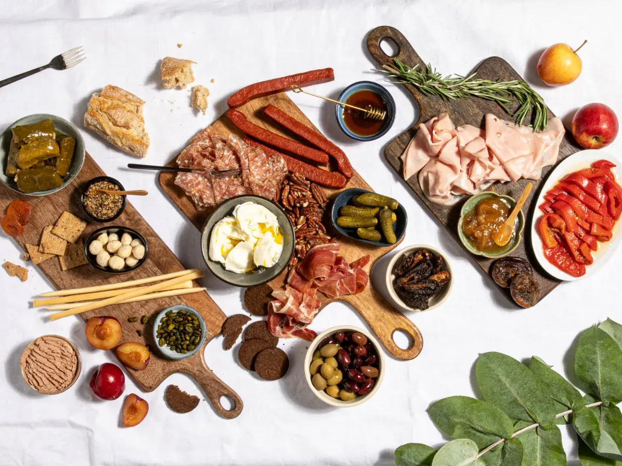 Mediterranes Fingerfood kalt: Eine &uuml;ppige Auswahl an Wurst, K&auml;se, Oliven, Fr&uuml;chten und Brot auf Holztellern.