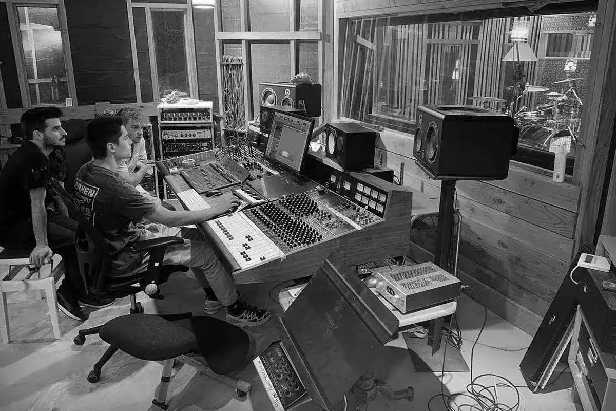 Tres j&oacute;venes trabajan en un estudio de grabaci&oacute;n, mezclando sonido en una consola. Un proyecto de **grado superior imagen** cobra vida.