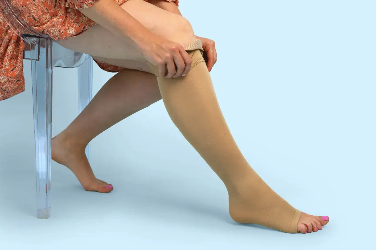 Frau zieht Kompressionsstrumpf an, eine Alternative zu Thrombose-Tabletten statt Spritze für den Flug.