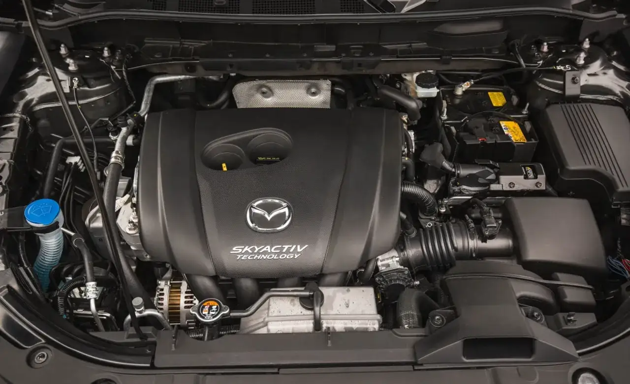 Silnik Skyactiv-G w Mazda 6 GJ. Widoczny jest czarny, plastikowy kolektor, logo Mazdy i napisy.