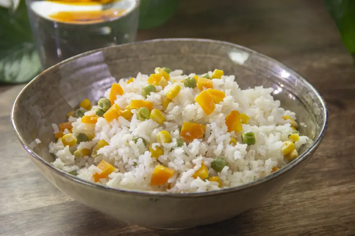 Un plato de arroz blanco con guisantes, ma&iacute;z y zanahoria en cubos. Una deliciosa y sencilla receta de arroz con verduras.