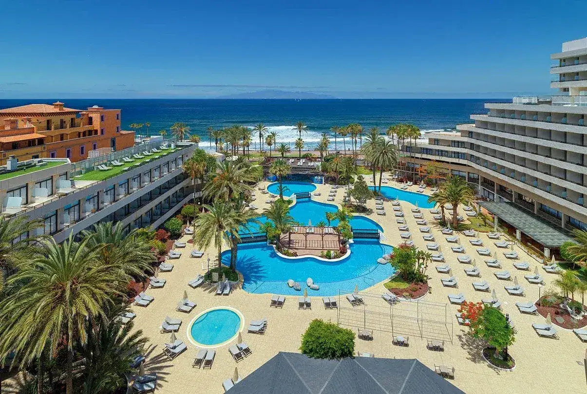 Resort con piscinas y palmeras en Tenerife. ¡Aprovecha las ofertas de viajes a Tenerife todo incluido 2x1 y disfruta del sol!