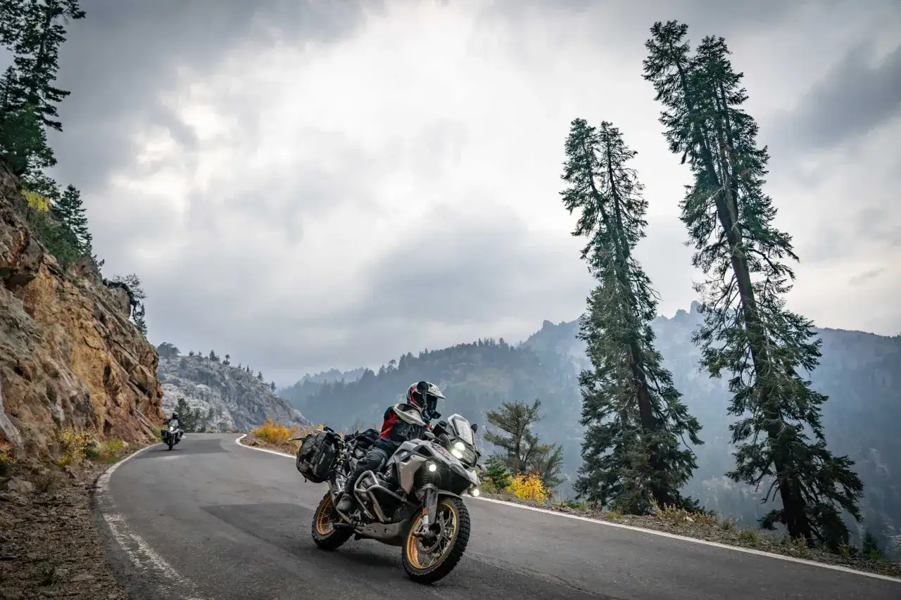Motociclista en una carretera montañosa con motos BMW modelos, disfrutando de la aventura.