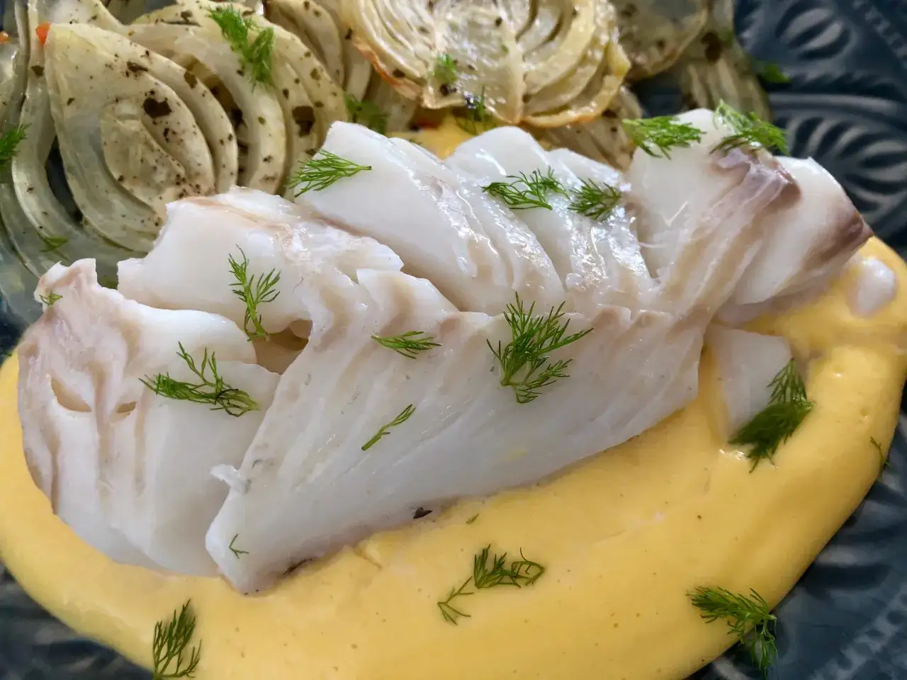 L&auml;ckert vit fisk serverad med kr&auml;mig s&aring;s och ugnsbakad f&auml;nk&aring;l, garnerad med dill.