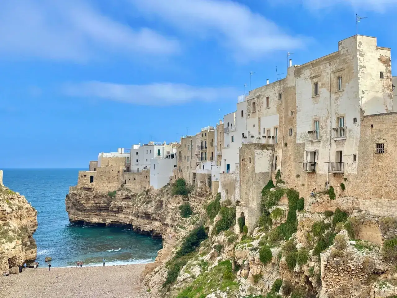 Case bianche a picco sul mare turchese, la famosa spiaggia di Polignano a Mare incastonata tra le rocce.