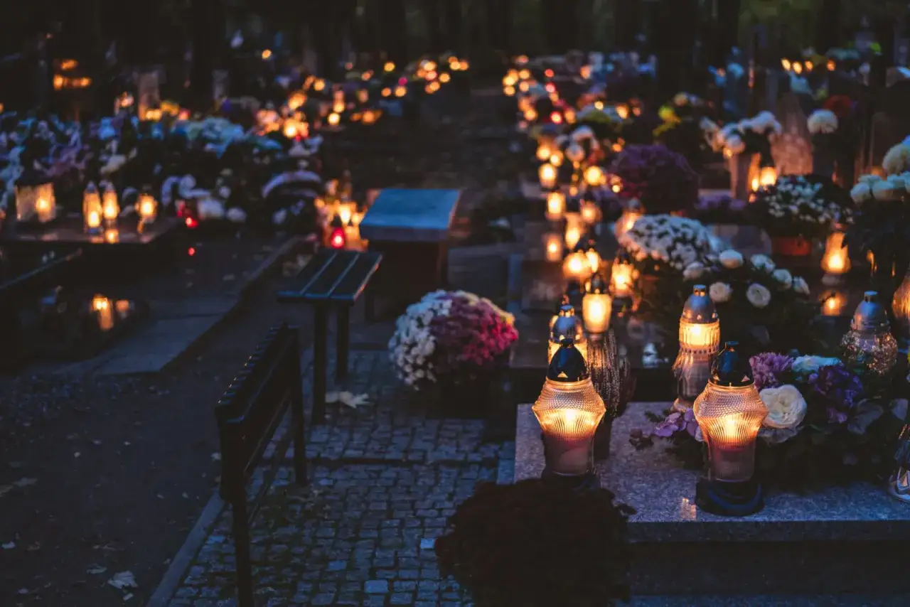Cmentarz nocą, pełen płonących zniczy i kwiatów. Wiele osób odwiedza groby bliskich, pielęgnując tradycję i wspominając zmarłych. Te przesądy cmentarne są ważną częścią kultury.