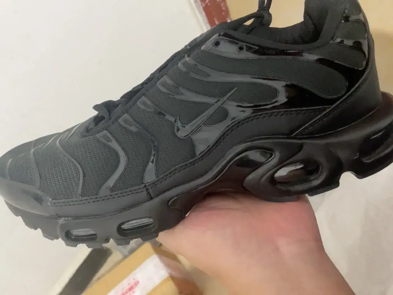 Schwarzer Nike TN Schuh in der Hand. Achte auf Details, um ein nike tn fake erkennen zu können.