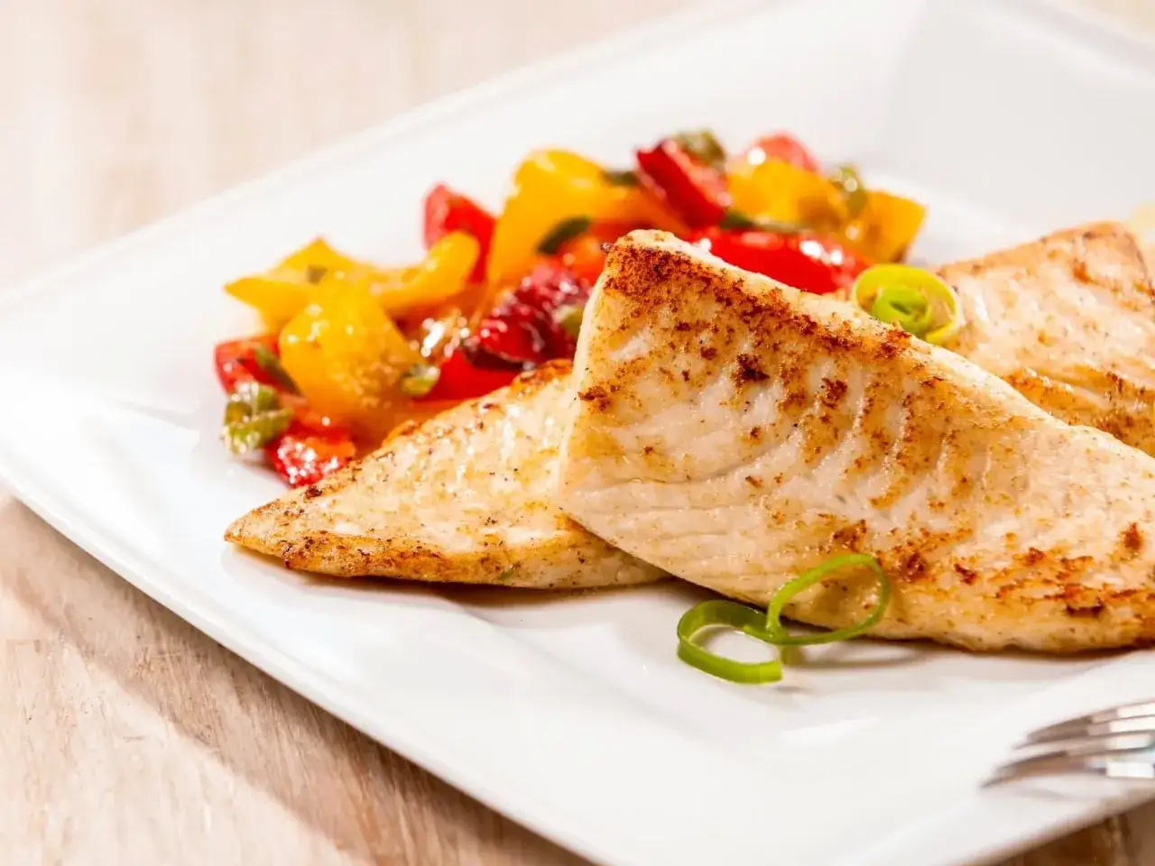 Smażona tilapia, czyli co to za ryba, podana z kolorowymi warzywami.