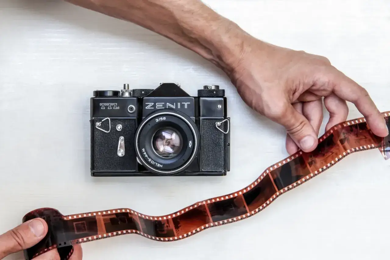 Dłonie trzymają kliszę do aparatu Zenit. Klasyczna fotografia analogowa w najlepszym wydaniu.