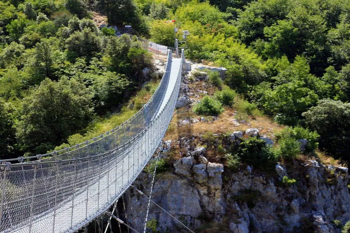 Un lungo ponte tibetano si snoda tra rocce e vegetazione lussureggiante, offrendo un'avventura mozzafiato nei dintorni di Salerno.