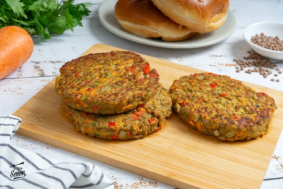 Tres hamburguesas de lentejas caseras, con trocitos de zanahoria y pimiento, listas para montar.
