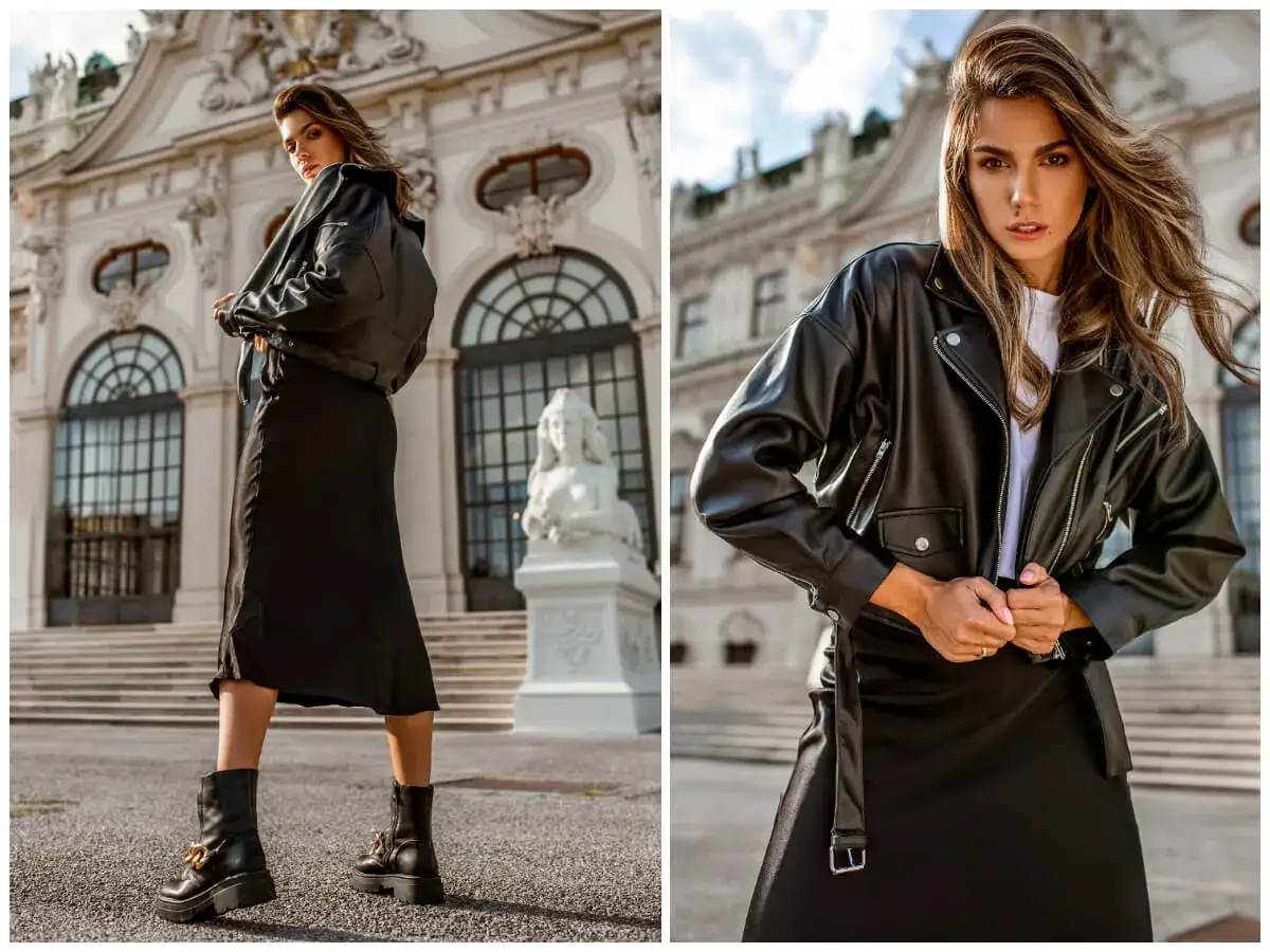 Elegancka bluzka z eko skóry w rockowym stylu, zestawiona z czarną spódnicą i botkami. Modelka pozuje na tle zabytkowej budowli.