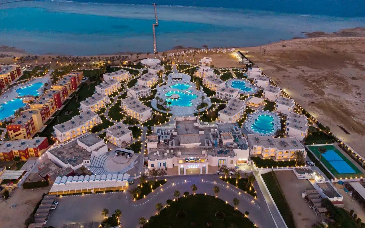 Luksusowy resort Casa Blue z basenami i budynkami oświetlonymi nocą, nad brzegiem morza.