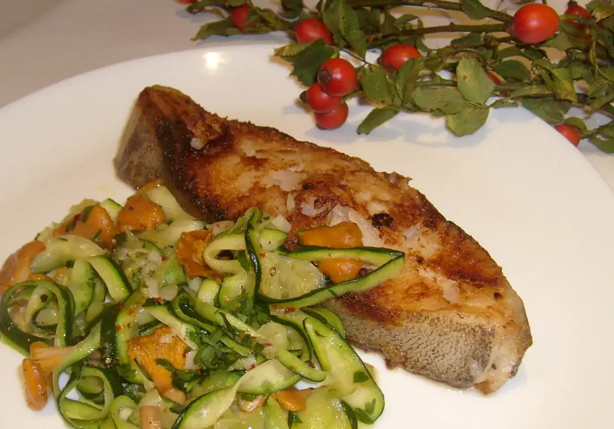 Złocisty halibut stek z chrupiącą skórką, podany z orzeźwiającą sałatką z cukinii i kurkami.