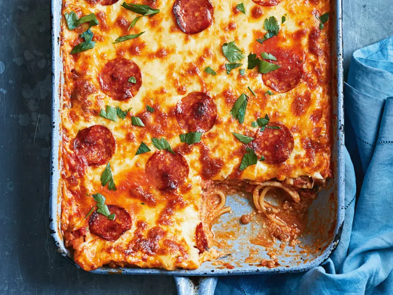 Herzhafter Spaghetti Pizza Auflauf mit geschmolzenem Käse und Pepperoni, garniert mit frischer Petersilie. Ein Genuss für die ganze Familie!