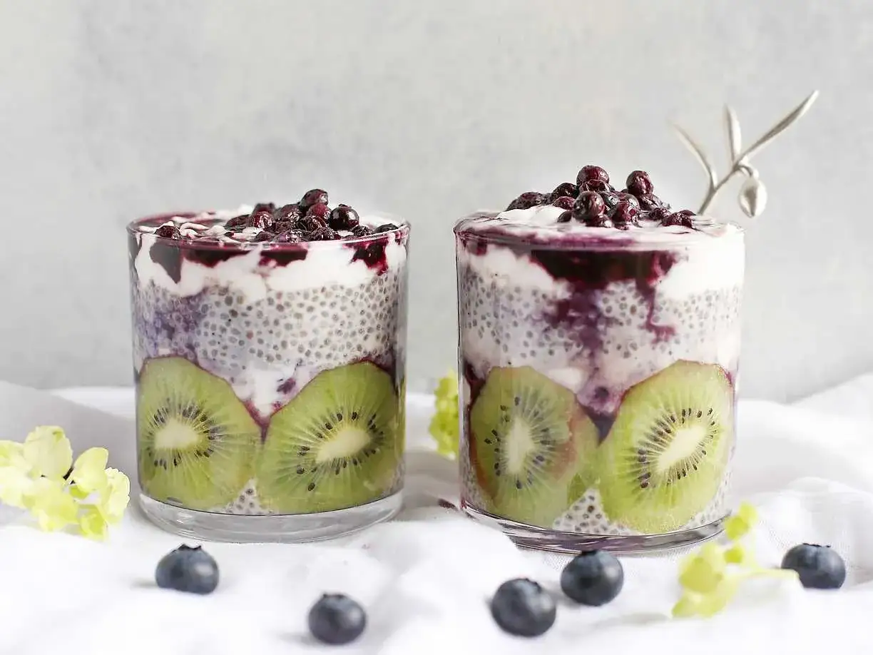 Två glas med chiapudding kvarg, kiwi och blåbär. En vacker och hälsosam frukost.