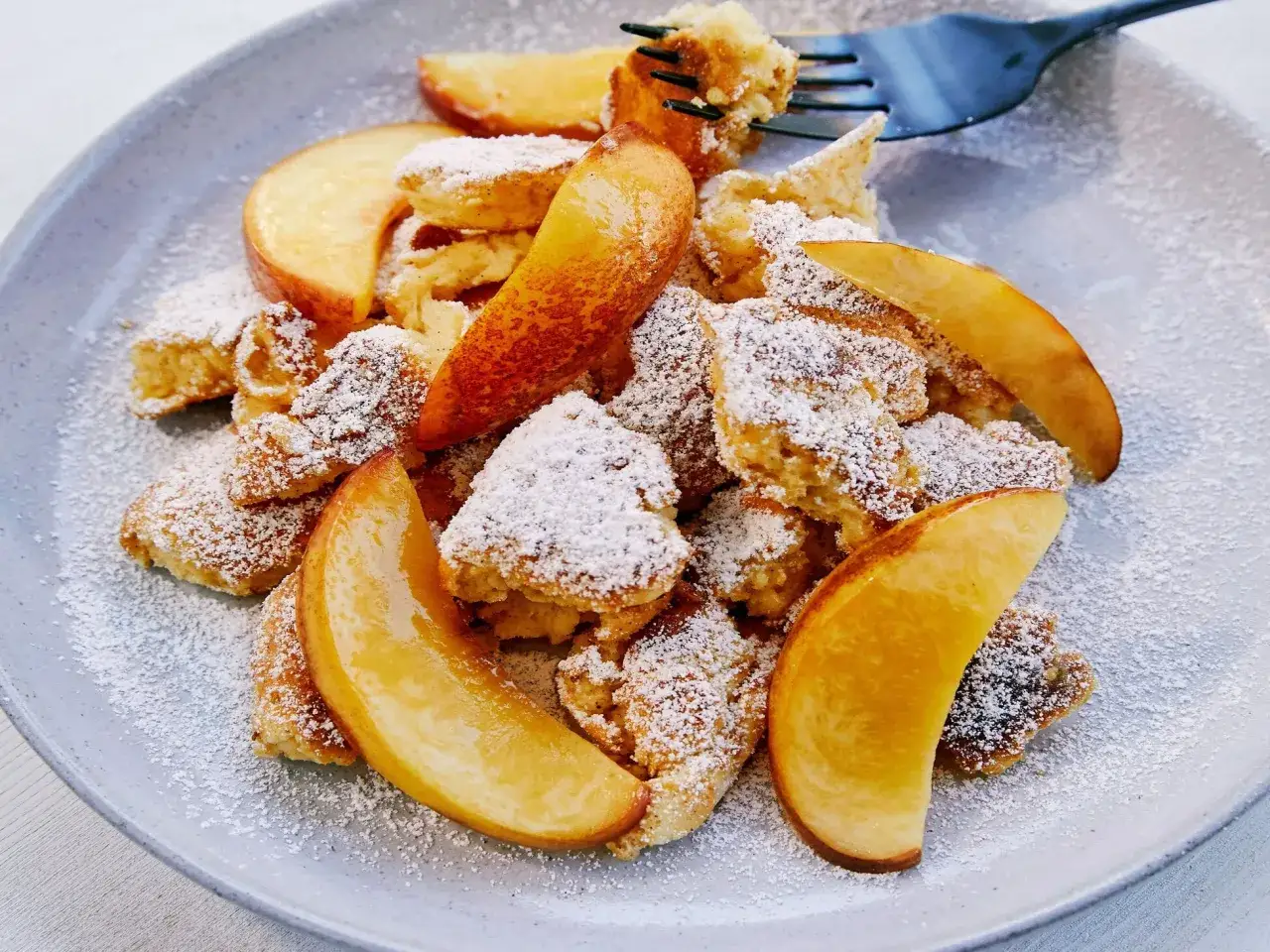 Kaiserschmarrn-Rezepte sind oft so lecker! Hier ein fluffiger Kaiserschmarrn mit Apfelspalten, best&auml;ubt mit Puderzucker.