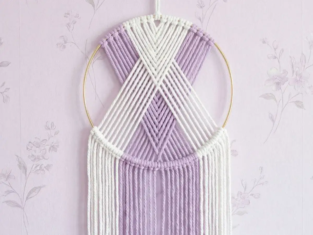 Delikatna makrama na k&oacute;łku w kolorach bieli i lawendy, ozdoba ścienna w stylu boho.