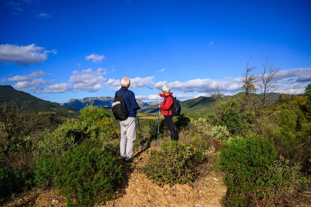 Un couple profite d'un week-end randonnée en amoureux, admirant le paysage montagneux sous un ciel bleu éclatant.