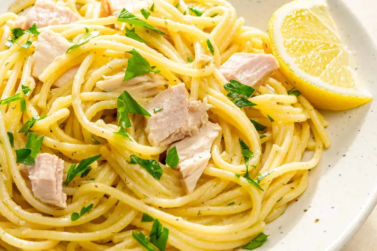 Pyszne spaghetti z tuńczykiem, posypane natką pietruszki i podane z plasterkiem cytryny. Idealna pasta z tuńczyka na szybki obiad.