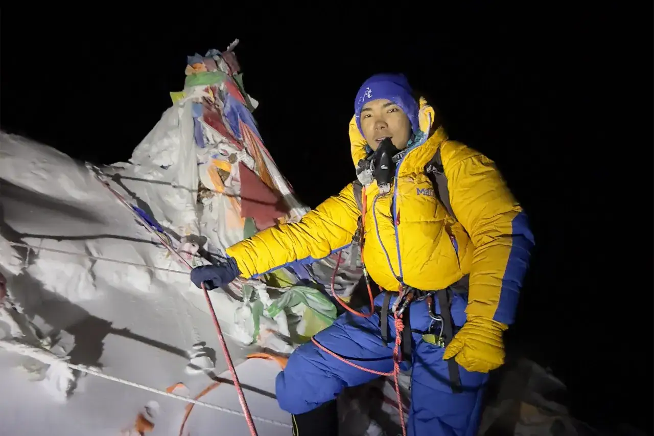 Młody himalaista w żółtej kurtce i niebieskiej czapce, z maską tlenową, wspina się po Mount Everest.