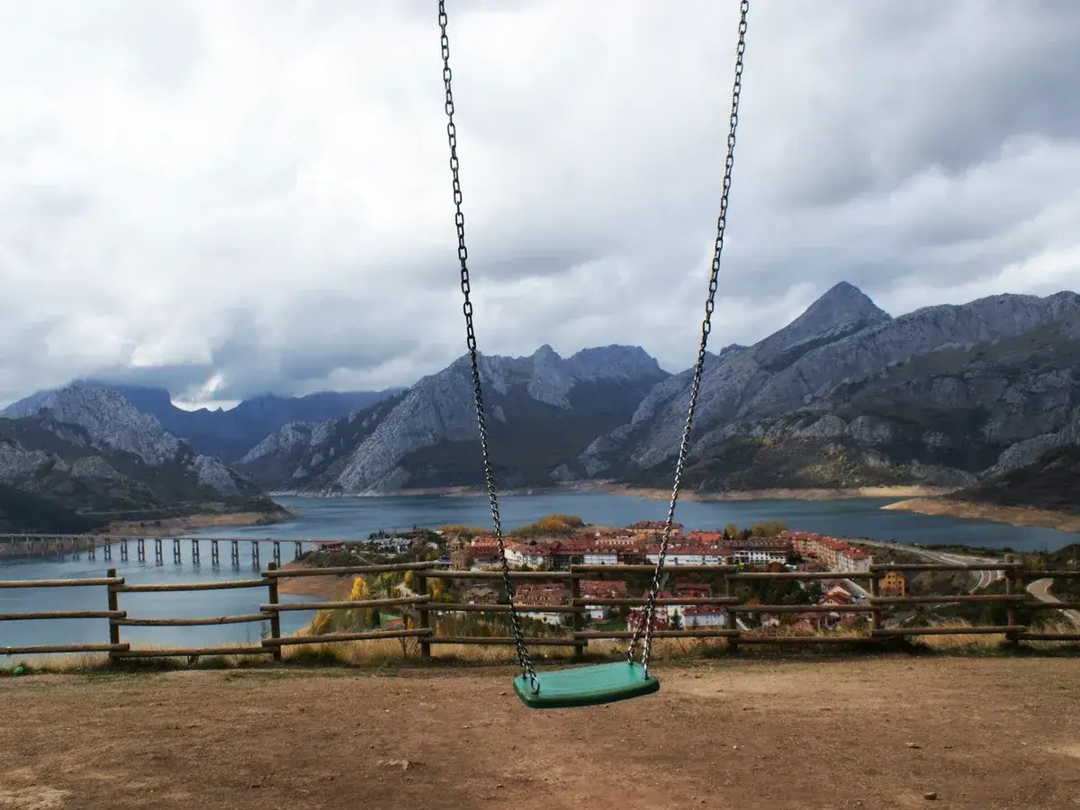 Un columpio vacío con vistas a un pueblo y montañas en Riaño.