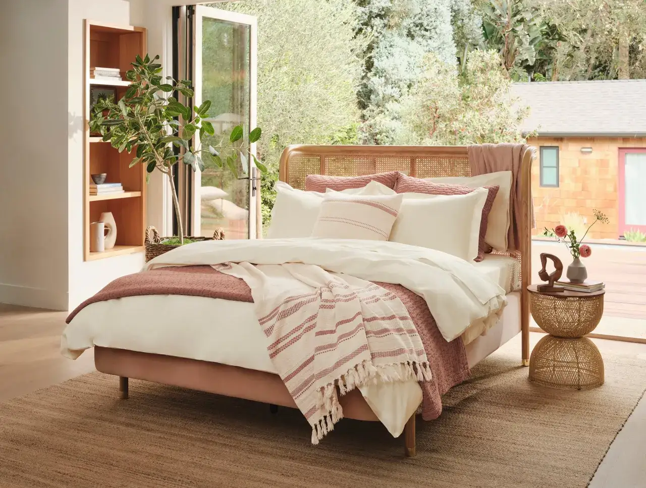 A cozy bedroom with a pink velvet bed, white bedding, and a striped throw. The best thread count for comforter ensures ultimate comfort.