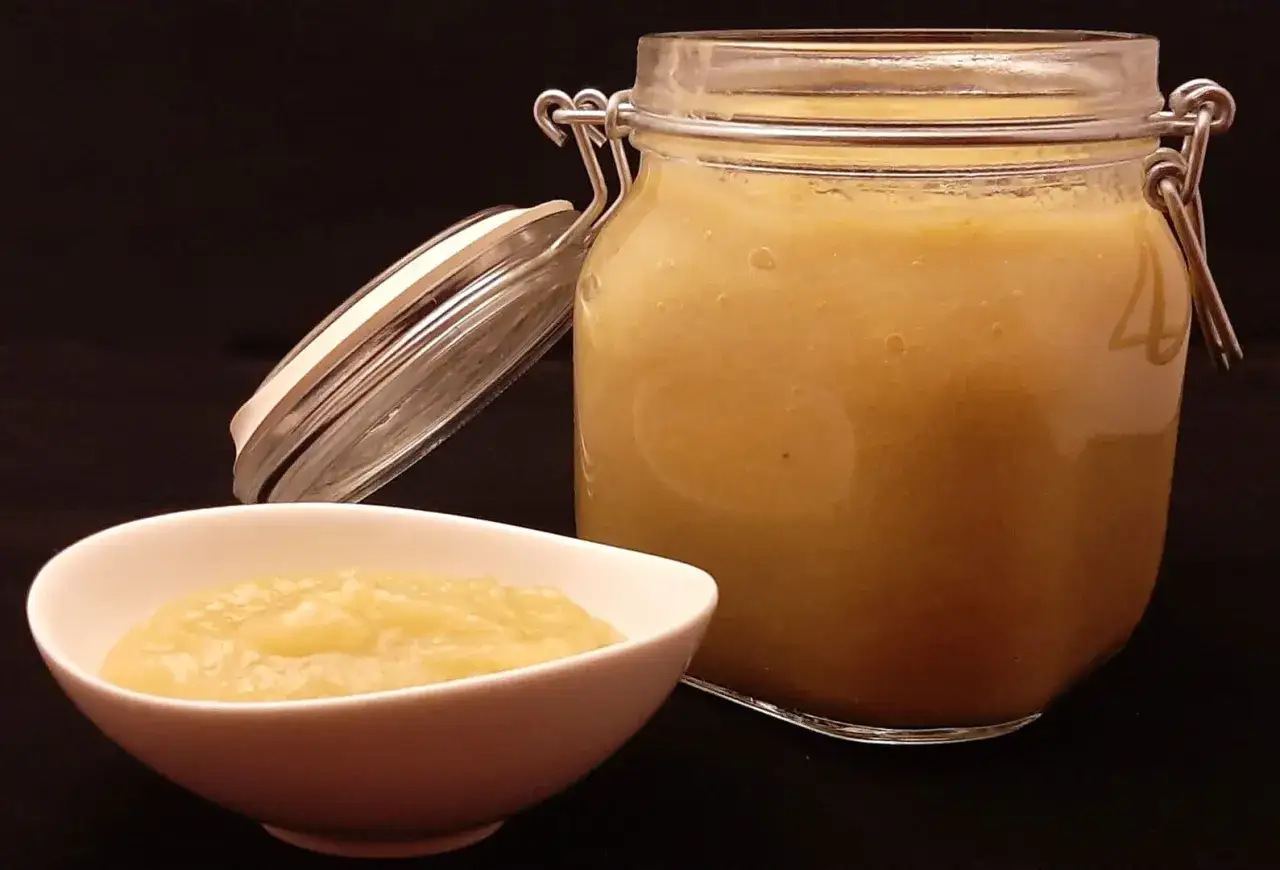 Un bocal ouvert et un bol de compote de rhubarbe maison, pr&ecirc;te &agrave; &ecirc;tre d&eacute;gust&eacute;e.