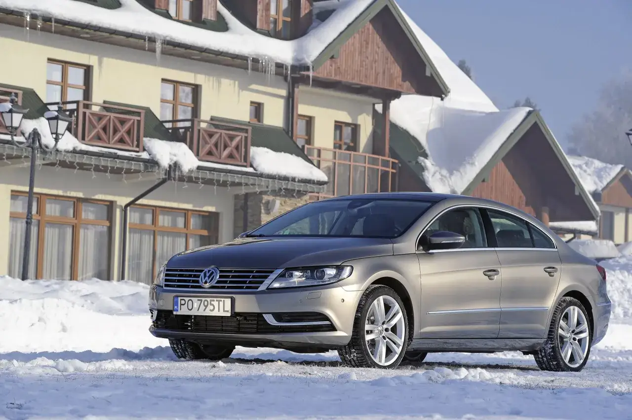 Elegancki Volkswagen Passat CC na tle zaśnieżonego pensjonatu.
