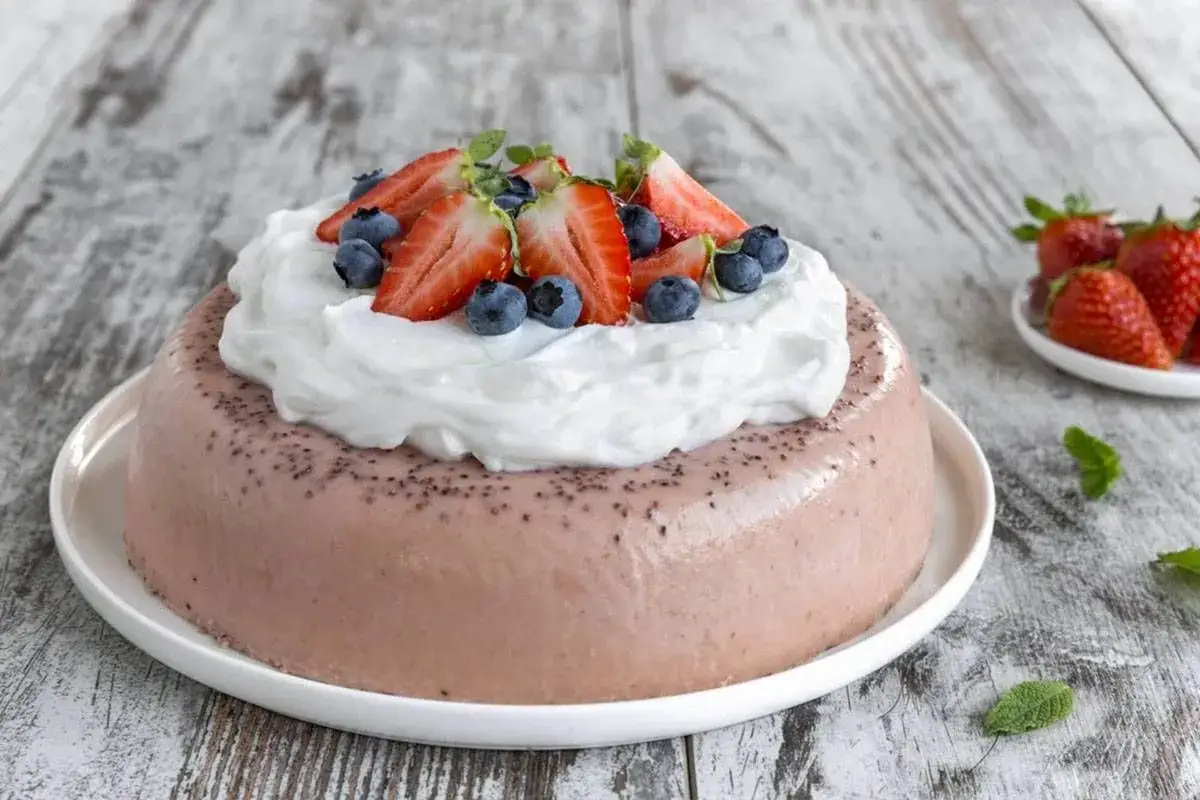 Delizioso bavarese alle fragole, guarnito con panna montata, fragole fresche e mirtilli.