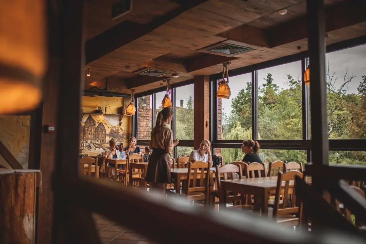Przytulne wnętrze z widokiem na zieleń. Idealne miejsce na obiad, jeśli szukasz polecane restauracje Bydgoszcz.