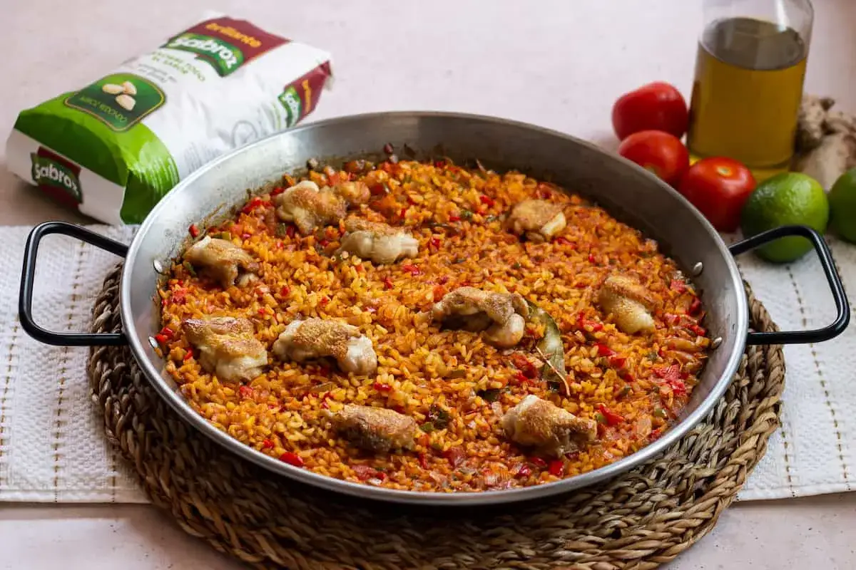 Paella de arroz con alitas de pollo, un plato lleno de sabor y color.