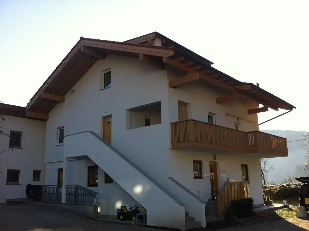 Casa con tetto in legno, ideale per un progetto di alzare tetto ecobonus. Scale esterne e balcone in legno.