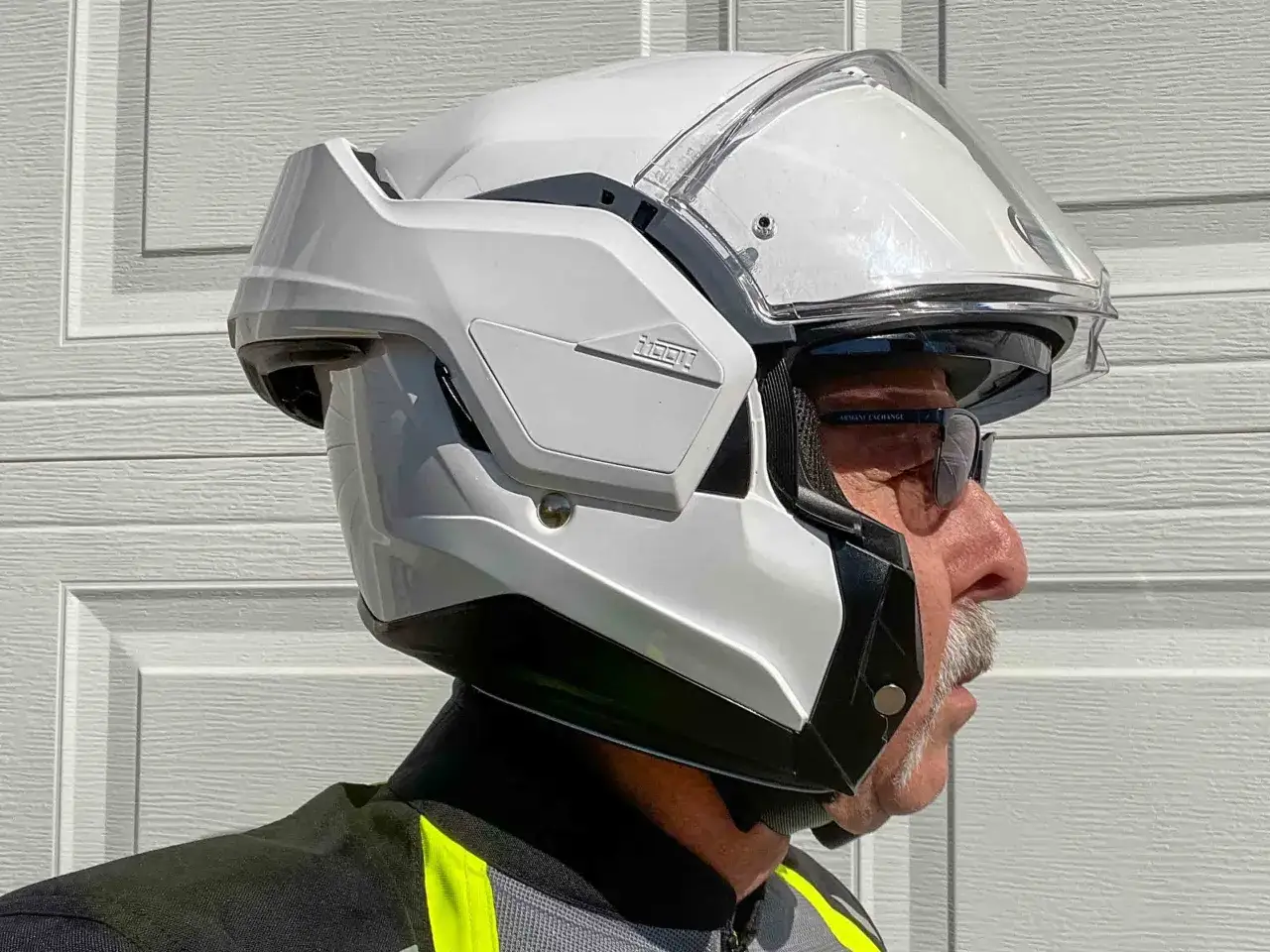 Hombre con un casco modular blanco de moto, con visera transparente y detalles negros.