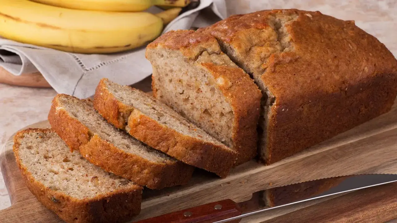 Ein saftiges Bananenbrot, perfekt f&uuml;r ein Bananenbrot Rezept ohne Zucker. Daneben liegen reife Bananen.
