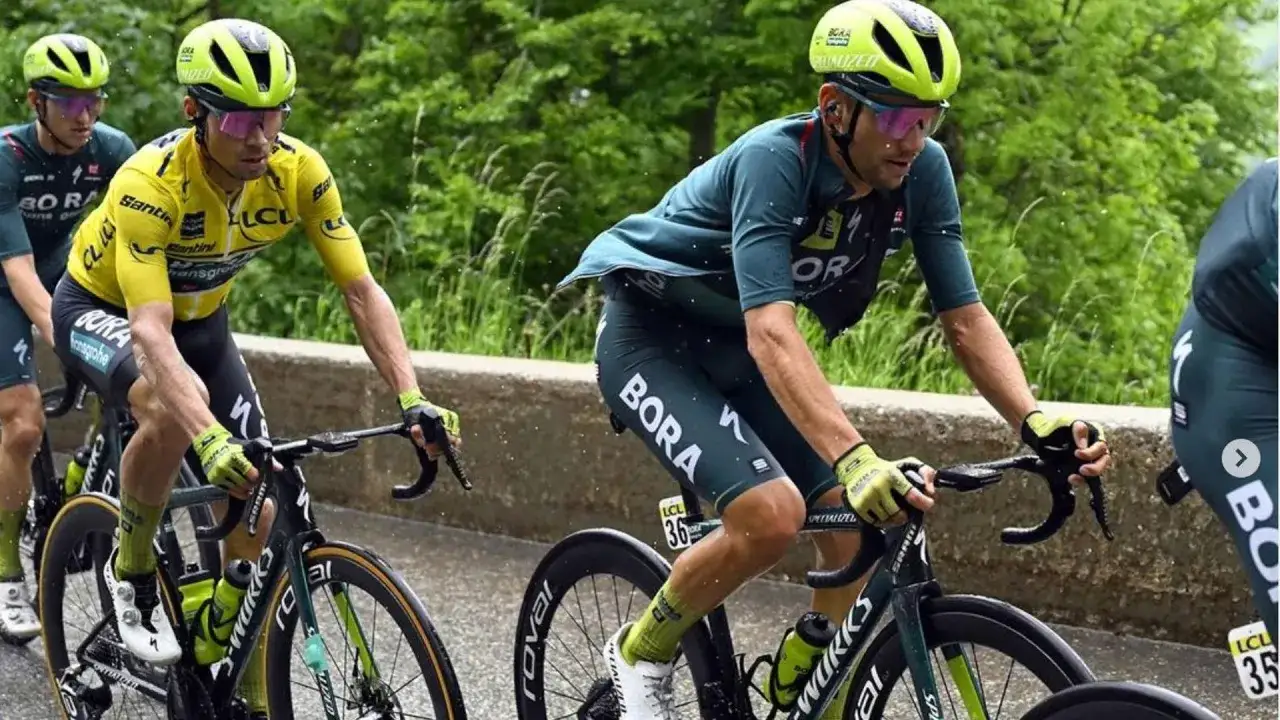 Ciclisti in gara, uno in maglia gialla, affrontano una salita. Concentrazione e fatica mentre vanno in bici.
