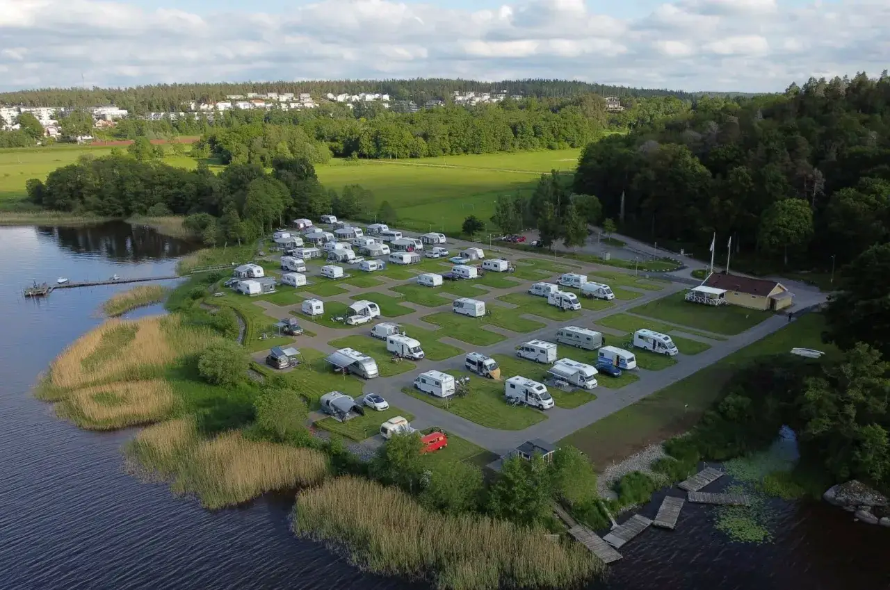 En campingplats vid en sjö nära Alingsås, med många husbilar och husvagnar uppställda på gröna platser.