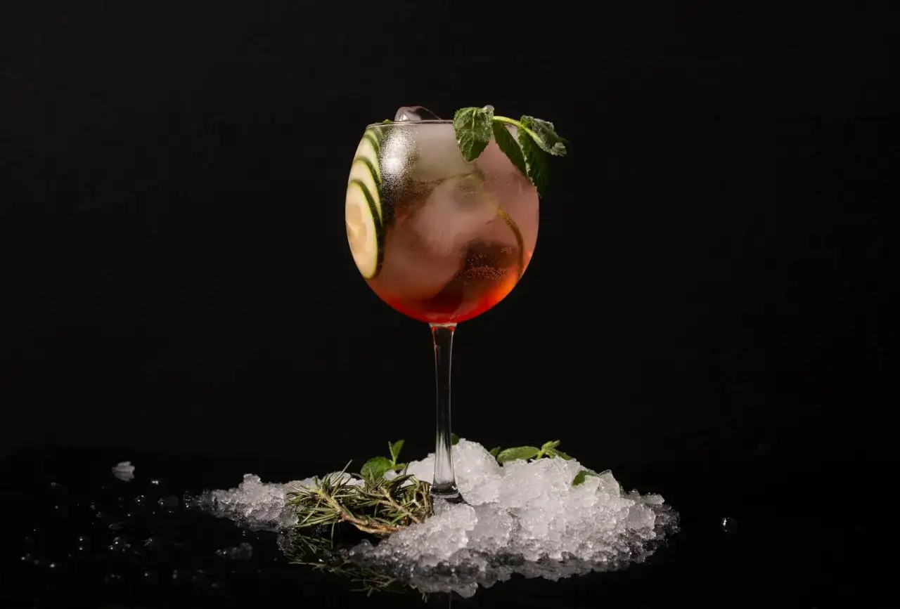 Orzeźwiający gin z tonikiem z plasterkami ogórka i miętą, z gałązką rozmarynu na lodzie. Skutki dodania świeżego rozmarynu do ginu z tonikiem są widoczne w aromacie i dekoracji.
