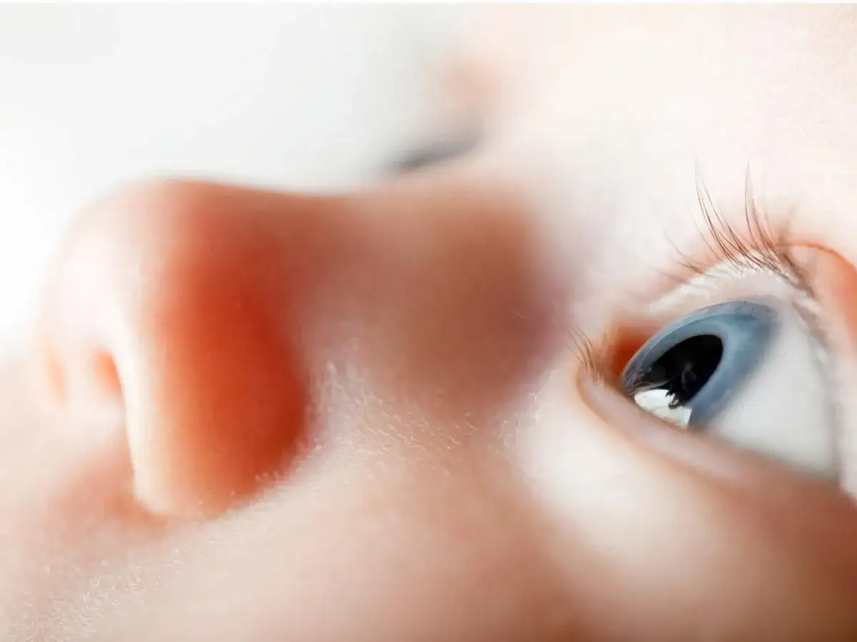 Occhi azzurri di un neonato, con un primo piano sul naso e sulle ciglia. Potrebbe sembrare falso strabismo nei neonati, ma &egrave; solo la prospettiva.