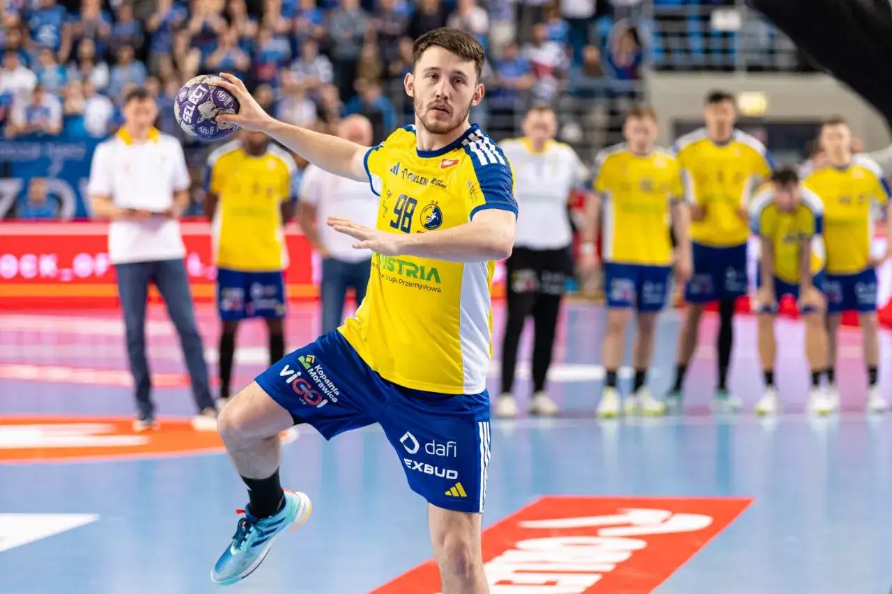 Piłkarz ręczny Vive Kielce z piłką, gotowy do rzutu. Kibice na trybunach czekają na Ligę Mistrzów. Sprawdźcie terminarz!