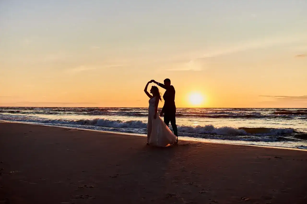 Para tańczy na plaży o zachodzie słońca. Romantyczny wypad we dwoje.